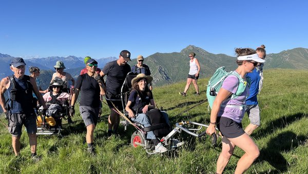 Eine Wandergruppe mit zwei Protreks marschieren über eine hügelige Wiese.