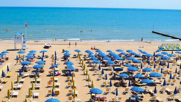 Ein gigantischer Sandstrand mit reihenweise Sonnenschirme und endlosem Meer im Hintergrund