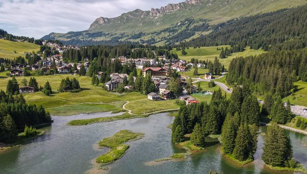 Das Dorf Valbella mit einem See im Vordergrund.