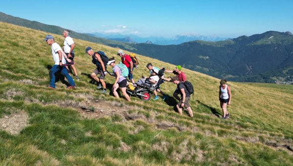 Eine Gruppe wandert über eine Wiese hoch auf einen Hügel.