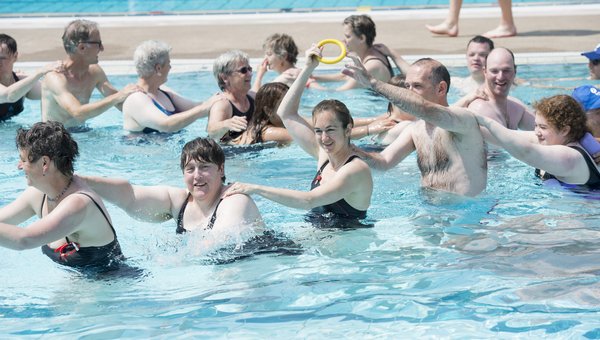Mehrere fröhliche Personen machen eine Polonaise im Wasser