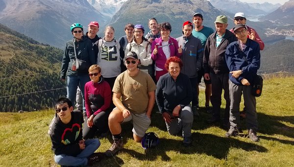Die Wandergruppe posiert auf einer Wiese. Im Hintergrund sind die Berge.