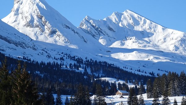 Blick in die verschneiten Berge bei strahlendem Sonnenschein und blauem Himmel.