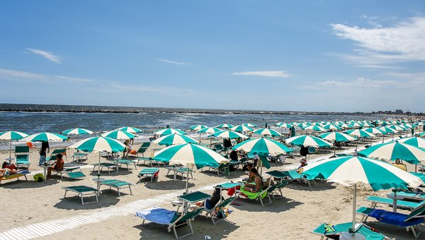 Sicht auf den privaten Sandstrand von Lido degli Scacchi mit den weiss-türkis Sonnenschirmen