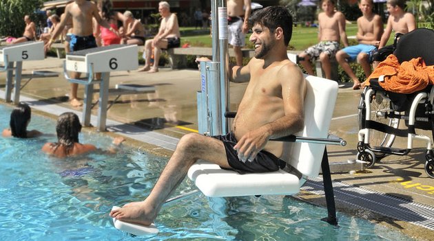 Ein Mann mit Gehbehinderung erhält Zugang zum Schwimmbecken mit einem Poollift