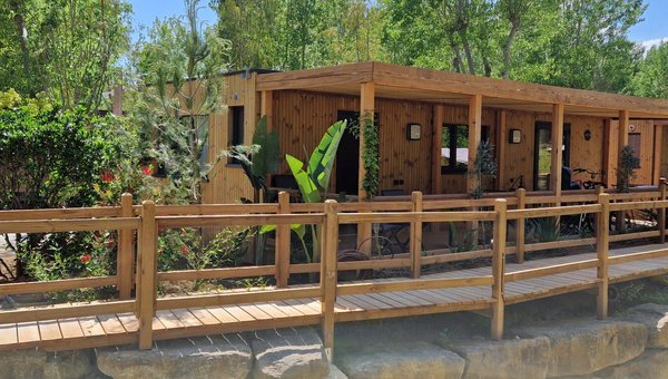 Blick auf die Mobilhomes aus Holz im Hintergrund sieht man Bäume Blick auf die Mobilhomes aus Holz im Hintergrund sieht man Bäume