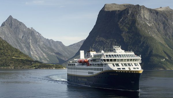 Schiff Havila Hurtigrute im Hintergrund die imposanten Berge Norwegens