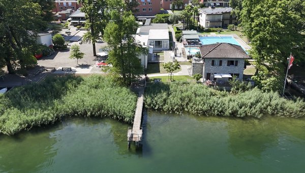 Luftansicht auf das Hotel mit Steg in den Luganersee im Vordergrund.