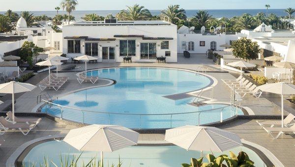 Bungalows Nautilus, Puerto del Carmen, Pool mit Bungalos, Palmen und Meer im Hintergrund