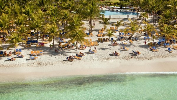 Sicht auf den wunderbarenSandstrand mit vielen Palmen, Pool und Hotel im Hintergrund