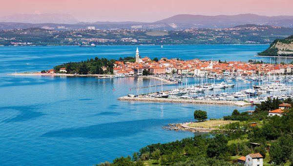 Blick auf Hafen und Altstadt an der Adriaküste. Im Vordergrund viel grüne Fläche