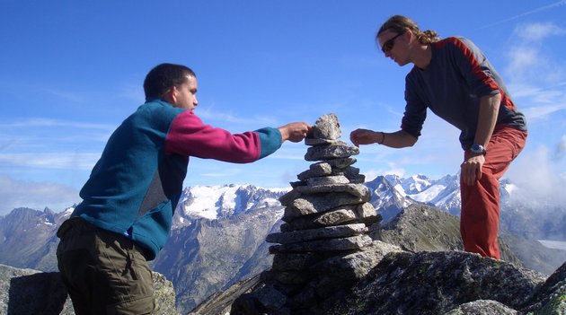 Zwei Wanderer bauen ein Steinmännchen