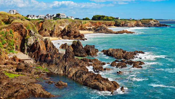 Sicht auf die zerklüftete Küste mit kleinen Sandstränden. Einige Häuser stehen über den Steilküsten.