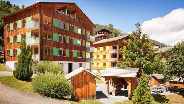 Sicht auf Häuser des Reka Feriendorfs Disentis mit den verschieden farbigen Fensterläden.